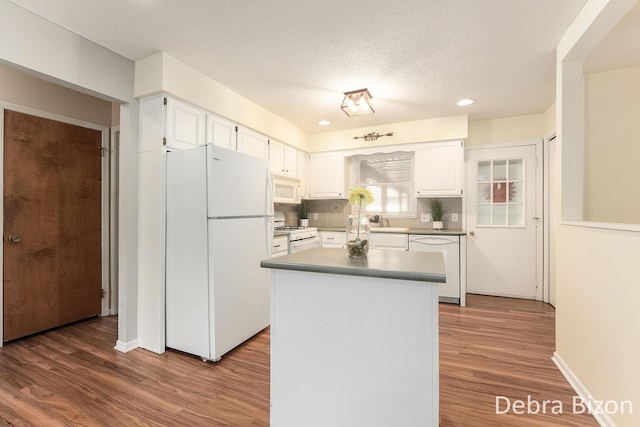 kitchen with decorative backsplash, white appliances, dark wood-type flooring, and white cabinets