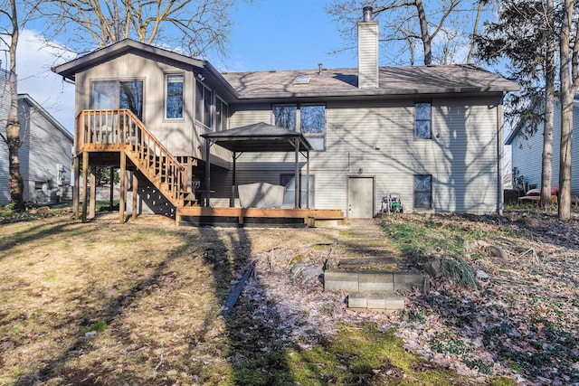 back of property featuring a shingled roof, a wooden deck, a gazebo, a lawn, and a chimney