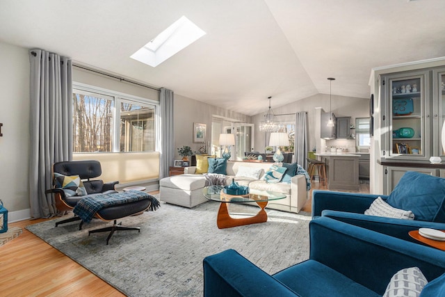 living area with an inviting chandelier, vaulted ceiling, and wood finished floors