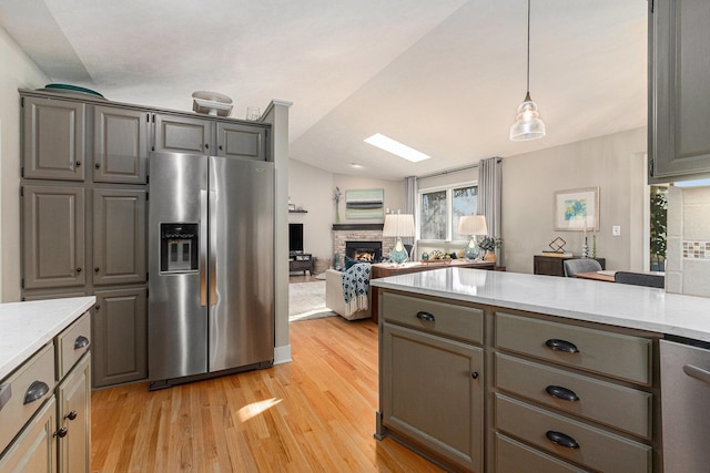 kitchen featuring stainless steel fridge, light wood-style floors, a fireplace, and gray cabinets