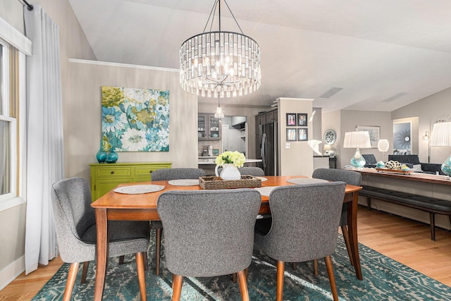 dining area featuring an inviting chandelier, lofted ceiling, and light wood-type flooring