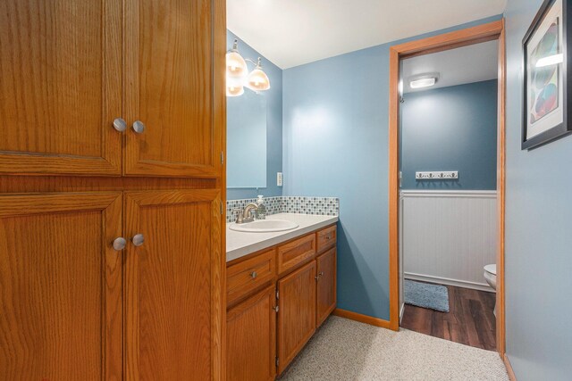 bathroom featuring a wainscoted wall, toilet, and vanity