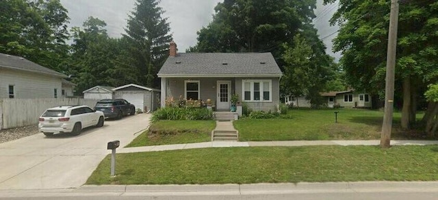 bungalow-style home with a detached garage, fence, a front yard, covered porch, and an outbuilding