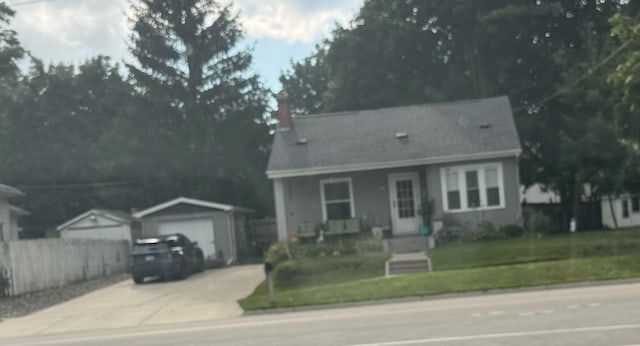 view of front of house with a detached garage, a front lawn, fence, covered porch, and an outdoor structure