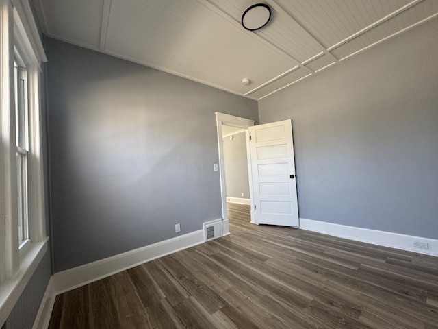 unfurnished room featuring visible vents, baseboards, and dark wood finished floors