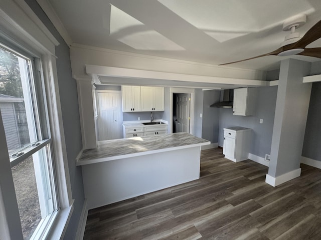 kitchen featuring a sink, dark wood finished floors, white cabinetry, a peninsula, and wall chimney exhaust hood