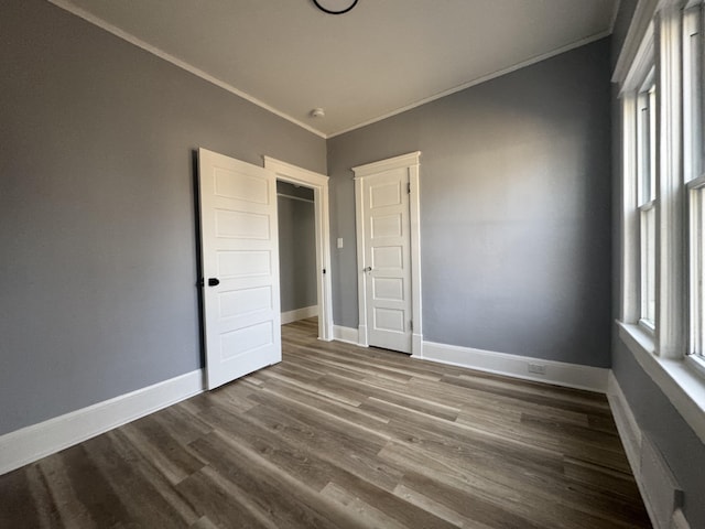 unfurnished bedroom with dark wood finished floors, multiple windows, baseboards, and ornamental molding