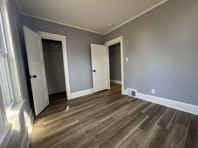 unfurnished bedroom featuring visible vents, baseboards, dark wood finished floors, and crown molding