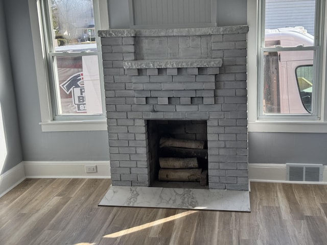 details featuring wood finished floors, a fireplace, visible vents, and baseboards