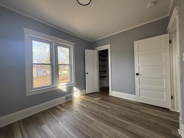 unfurnished bedroom with dark wood-style floors, visible vents, and ornamental molding