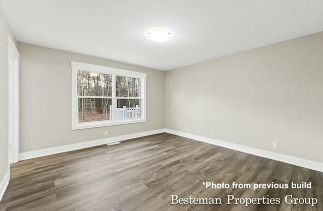 empty room featuring visible vents, wood finished floors, and baseboards