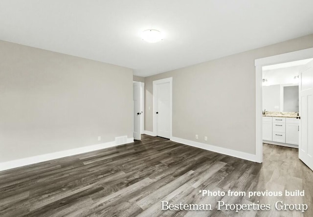 unfurnished bedroom featuring visible vents, connected bathroom, baseboards, and wood finished floors