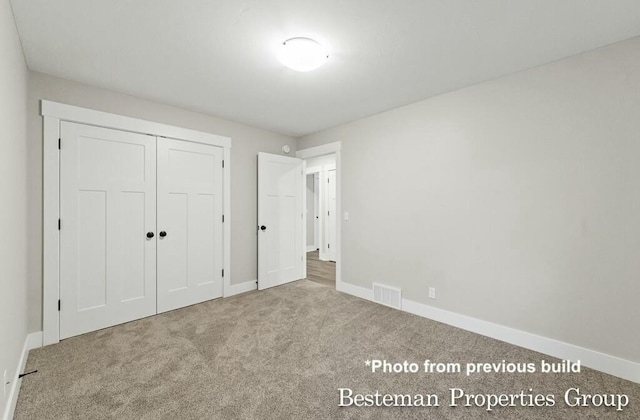 unfurnished bedroom featuring a closet, carpet flooring, baseboards, and visible vents