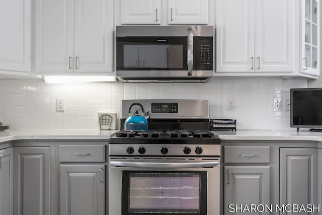 kitchen with decorative backsplash, white cabinetry, gray cabinets, and appliances with stainless steel finishes