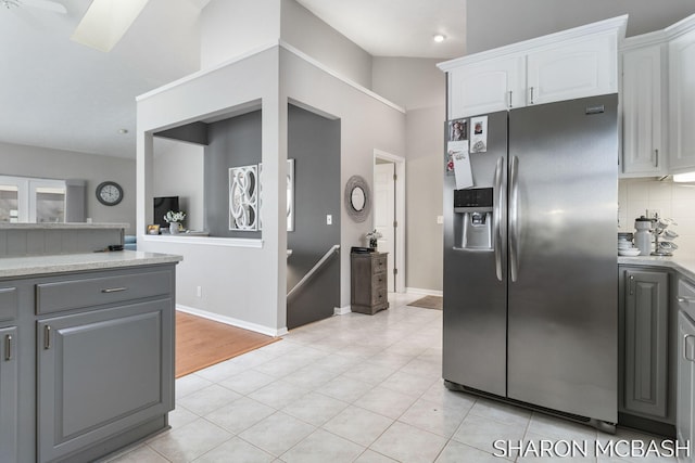 kitchen with gray cabinets, light countertops, stainless steel fridge, white cabinetry, and tasteful backsplash