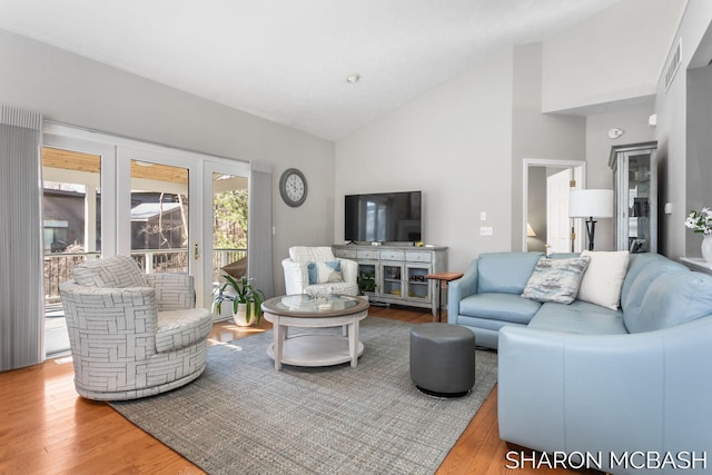 living room with visible vents, high vaulted ceiling, and wood finished floors