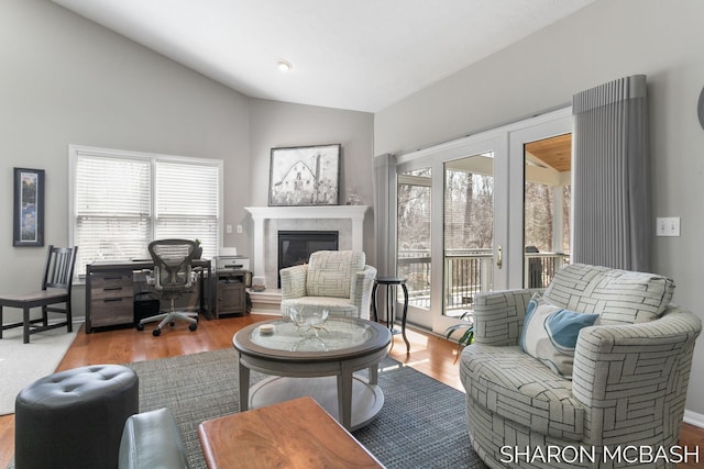 living room featuring a glass covered fireplace, lofted ceiling, wood finished floors, and a healthy amount of sunlight