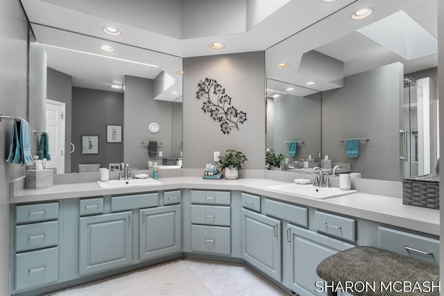 full bath featuring double vanity, recessed lighting, a skylight, and a sink