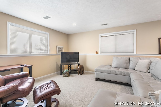 carpeted living room with visible vents, a textured ceiling, and baseboards