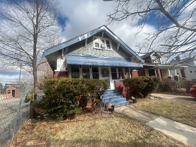 bungalow-style house with brick siding, covered porch, and fence