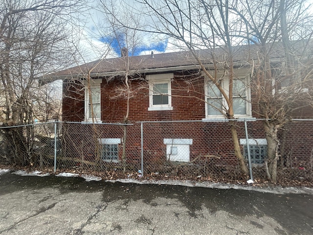 view of side of home with brick siding and fence