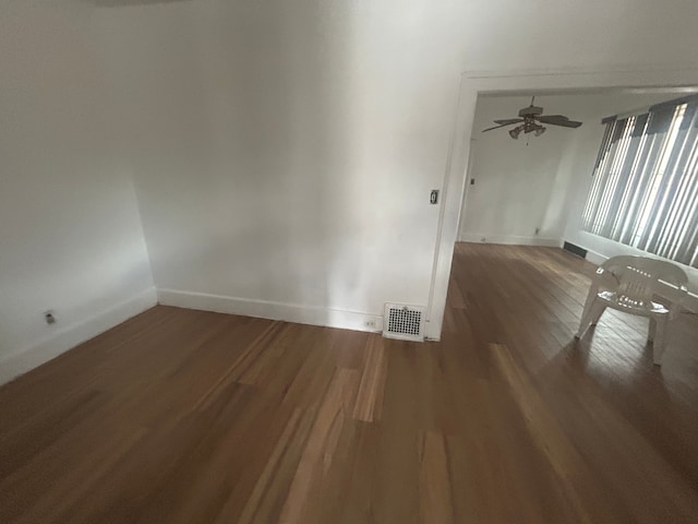 spare room with visible vents, ceiling fan, baseboards, and wood finished floors