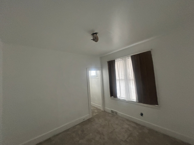 spare room featuring visible vents, baseboards, and carpet