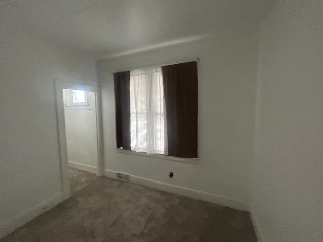 carpeted spare room with visible vents and baseboards