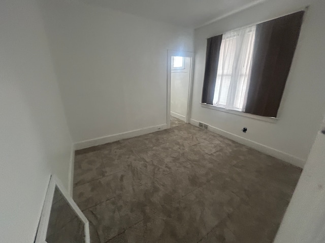 carpeted empty room featuring visible vents and baseboards