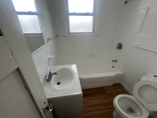 full bath with toilet,  shower combination, wood finished floors, and vanity