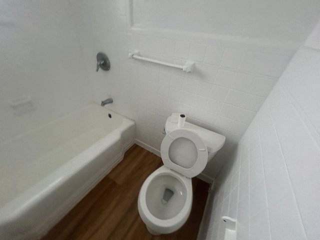 full bath featuring shower / bathing tub combination, toilet, tile walls, and wood finished floors