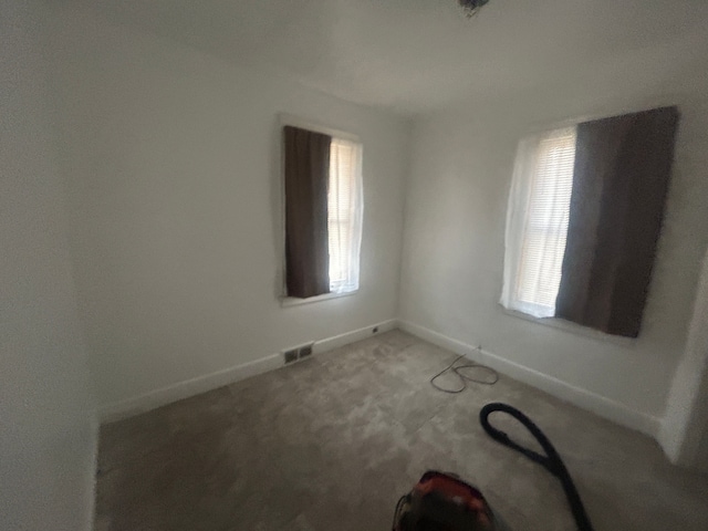 empty room featuring visible vents, carpet, and baseboards