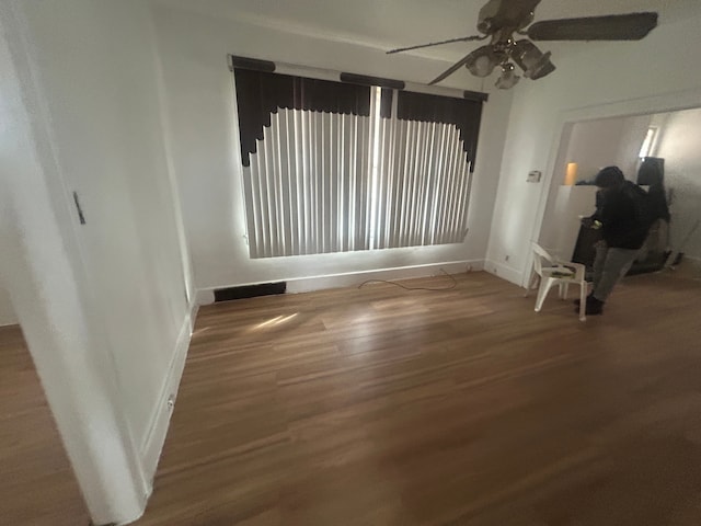 empty room with ceiling fan, baseboards, and wood finished floors