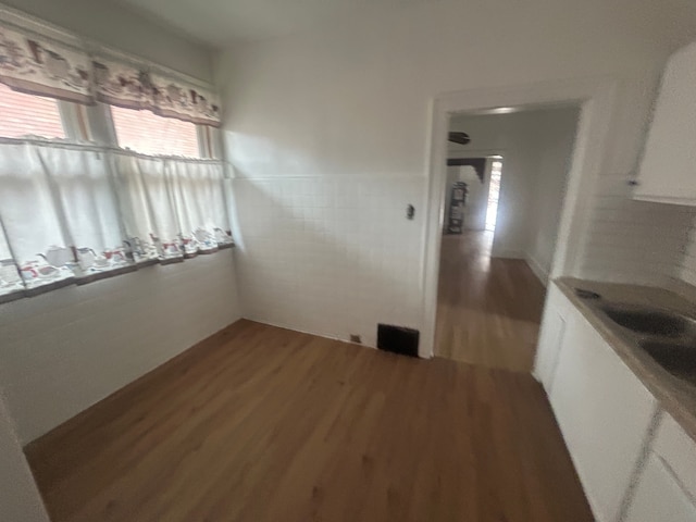 unfurnished dining area featuring visible vents, wainscoting, tile walls, and wood finished floors