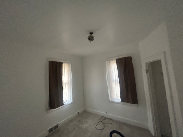 empty room featuring visible vents, plenty of natural light, and baseboards