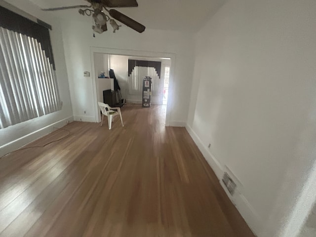 interior space with a ceiling fan, wood finished floors, and baseboards