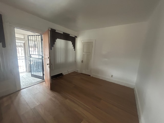 spare room with baseboards and wood finished floors