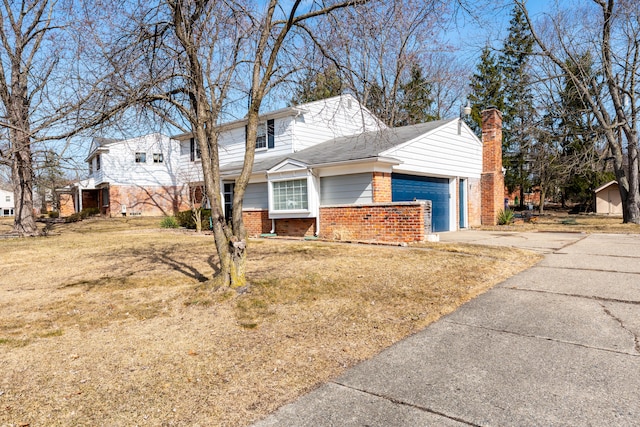 traditional home with a front yard, an attached garage, a chimney, concrete driveway, and brick siding