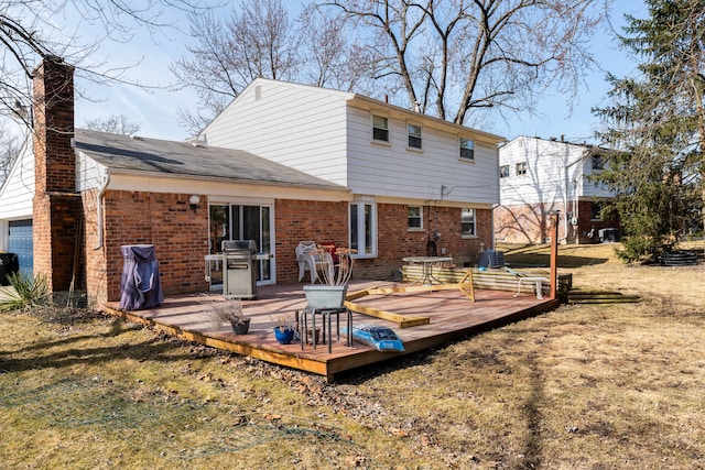 back of house with brick siding, a lawn, and a deck