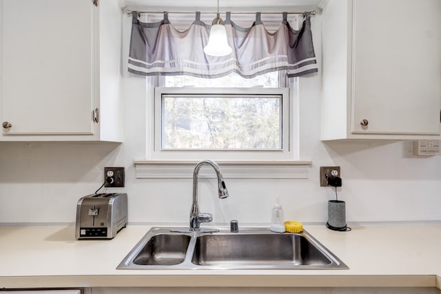 kitchen with white cabinetry, light countertops, and a sink