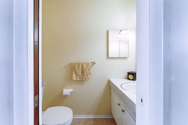 bathroom featuring toilet, vanity, and baseboards