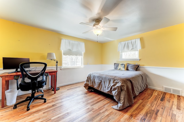 bedroom featuring multiple windows, wood finished floors, visible vents, and baseboards