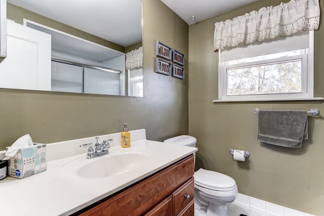 bathroom featuring a shower with door, toilet, and vanity