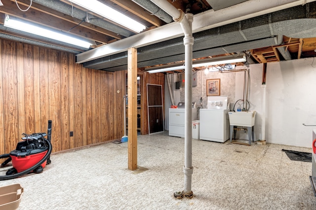 basement with washer and clothes dryer, wooden walls, tile patterned floors, and a sink