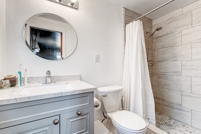 full bath featuring a tile shower, toilet, and vanity