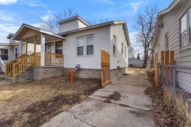 view of front of house with covered porch, driveway, and fence