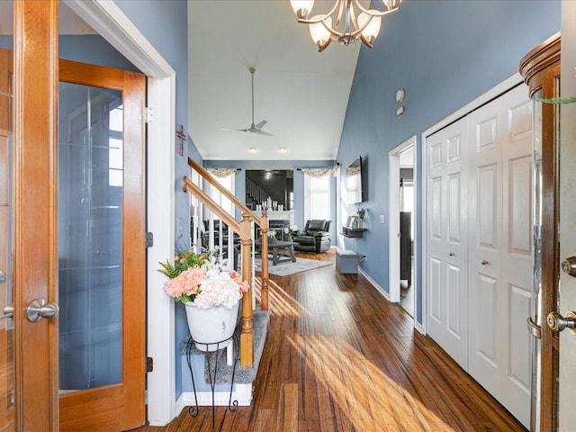 entryway featuring lofted ceiling, ceiling fan with notable chandelier, hardwood / wood-style floors, stairway, and baseboards