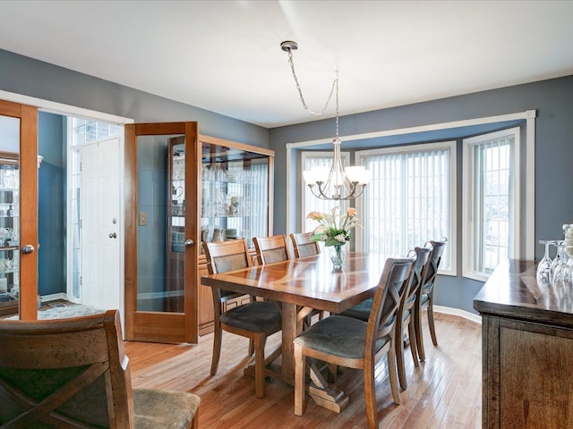 dining space featuring baseboards, an inviting chandelier, and light wood-style flooring