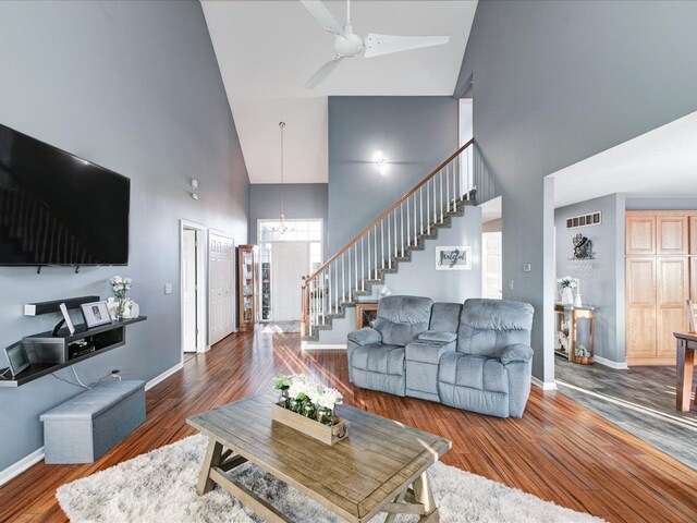 living room featuring stairway, baseboards, visible vents, and wood finished floors