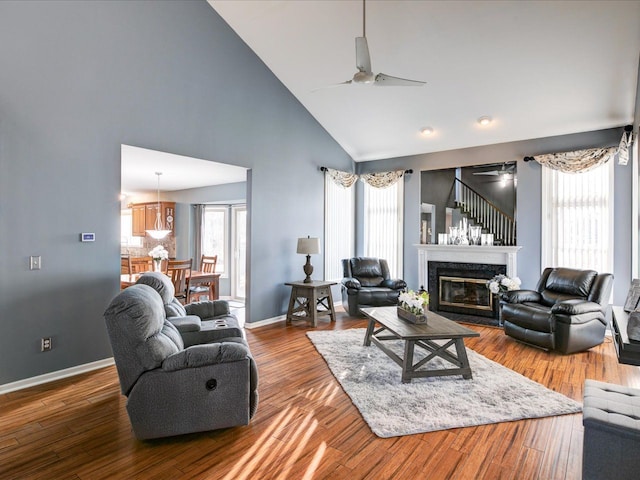 living area featuring baseboards, dark wood-type flooring, ceiling fan, and high vaulted ceiling